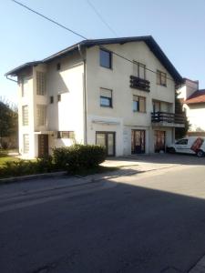 a white building with a car parked in front of it at Apartman Brazil in Bihać
