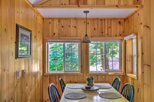 a dining room with a table and chairs and windows at Elk Hideaway Ashford Cottage with Hot Tub! in Ashford