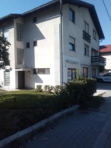 a white building with a car parked in front of it at Apartman Brazil in Bihać