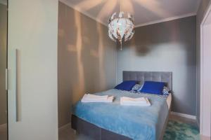 Schlafzimmer mit einem Bett mit blauer Bettwäsche und einem Kronleuchter in der Unterkunft Apartament Perłowy in Świnoujście