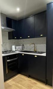 a kitchen with black cabinets and a sink at The Portside Apartment in Greenock