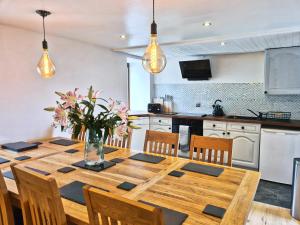 a dining room table with chairs and a kitchen at Luib House. Spacious Self-catering by the sea. in Broadford