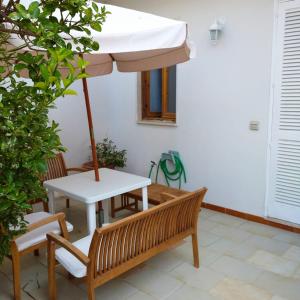 un tavolo e una panca con ombrellone di Casa Degli Ulivi a Otranto