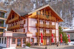 un grande edificio in legno con balcone e bandiere rosse di Gasthof Zwieselstein a Sölden