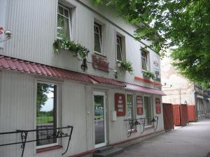 un edificio bianco con fiori alle finestre e una strada di Pie Jāņa Brāļa a Liepāja