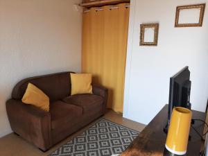 ein Wohnzimmer mit einem braunen Sofa und einem TV in der Unterkunft Entre port et village in Gruissan
