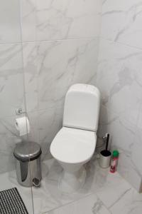 a white bathroom with a toilet and a trash can at Papli Apartments in Pärnu