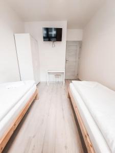 two beds in a room with a table and a tv at Apartament Kraków Arena No. 100 in Krakow