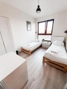 a white room with two beds and a window at Apartament Kraków Arena No. 100 in Krakow