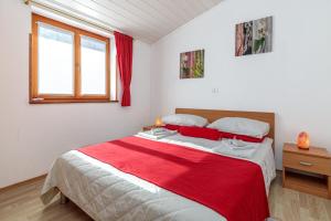 - une chambre avec un grand lit et une couverture rouge dans l'établissement Apartments Sveti Leonard, à Oprtalj