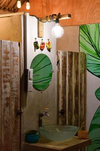 baño con lavabo verde y pared con plantas en Hotel El Delfin, en Monterrico