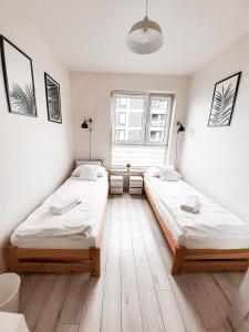 two beds in a room with a window at Apartament Kraków Arena in Krakow