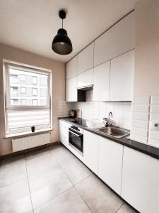 a kitchen with white cabinets and a sink and a window at Apartament Kraków Arena in Krakow