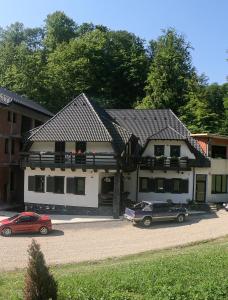 a building with two cars parked in front of it at Băile Puturoasa in Vama