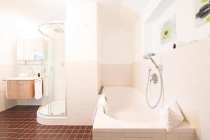 a white bathroom with a shower and a tub at Ludwigschlössl in Garmisch-Partenkirchen