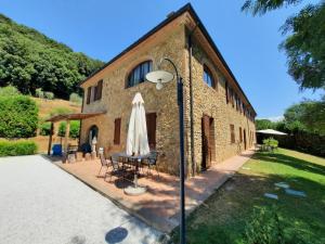 a brick building with a table and a umbrella at Il Casolare Val Di Mare in Riparbella