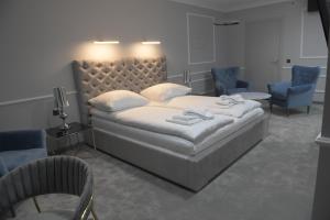 a bedroom with a large bed and two blue chairs at Atmosfera Apartament 1 i 2 in Bytów