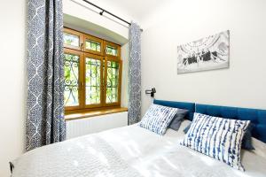 sypialnia z łóżkiem z niebieskim zagłówkiem i oknem w obiekcie Apartamenty Stara Apteka w Stroniu Śląskim