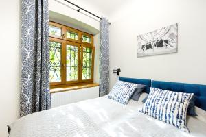 a bedroom with a bed with a blue headboard and a window at Apartamenty Stara Apteka in Stronie Śląskie