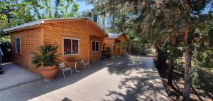 a small wooden cabin with chairs and a patio at Cabañas swissminiatur in Cacheuta