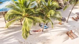 a person laying under two palm trees on a beach at Azul Over-the-Water Resort in Bocas Town