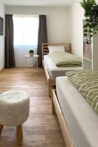 1 Schlafzimmer mit 2 Betten, einem Stuhl und einem Fenster in der Unterkunft Modern apartment in a charming old town setting in Altstätten