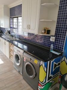 a kitchen with a washing machine and a sink at JB Countrylife Accommodation in Centurion