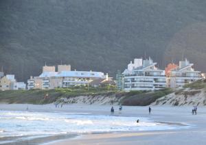 a group of people on a beach with buildings at Apartamento a beira mar completo com churrasqueira in Florianópolis