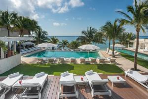 uma imagem de uma piscina de resort com espreguiçadeiras e o oceano em Blue Diamond Luxury Boutique - All Inclusive Adults Only em Playa del Carmen