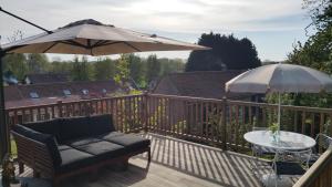 eine Terrasse mit einem Sofa, einem Sonnenschirm und einem Tisch in der Unterkunft Aux Nobles Acacias in Épagne-Épagnette