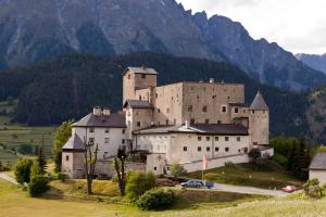 a large castle on a hill with mountains in the background at Schloss Naudersberg in Nauders