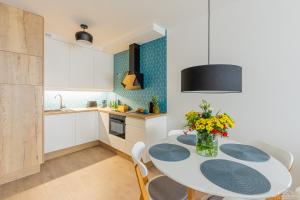 a kitchen with a table with chairs and a vase of flowers at Seaway Apartments - Miodowy Dom - Kołobrzeg in Kołobrzeg