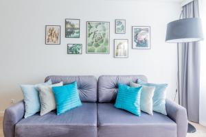 un sofá con almohadas azules y blancas en la sala de estar. en Seaway Apartments - Miodowy Dom - Kołobrzeg en Kołobrzeg