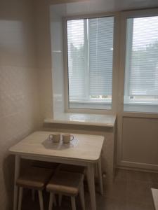 una mesa con dos tazas en una habitación con dos ventanas en Modern fresh-new appartment near the park Sofievka, en Uman