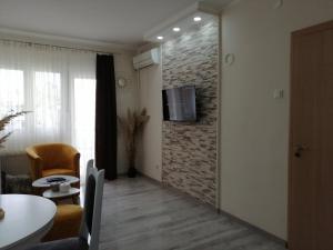 uma sala de estar com televisão numa parede de tijolos em Apartman Ži-Zo em Vršac