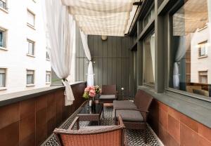 d'un balcon avec des chaises et une table fleurie. dans l'établissement Heart Milan Apartments Duomo Terrace, à Milan