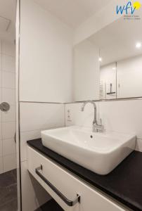 a white bathroom with a sink and a shower at Haus Talita - Wohnung BRAVO in Juist
