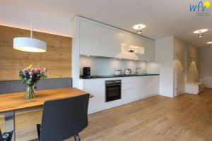 a kitchen with a wooden table and a vase of flowers at Haus Talita - Wohnung ZULU in Juist +9 photos