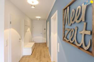 a hallway with a blue wall with a sign on it at Haus Talita - Wohnung ZULU in Juist