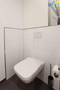 a white toilet in a white tiled bathroom at Haus Talita - Wohnung SIERRA in Juist