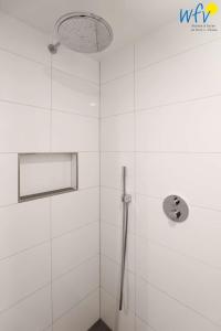 a bathroom with a shower with white tiles at Haus Talita - Wohnung LIMA in Juist