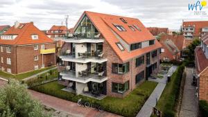 an apartment building with an orange roof in a city at Haus Talita - Wohnung LIMA in Juist +6 photos