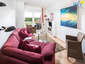 a living room with a red couch and chairs at Haus Ebbe und Flut A - Ferienwohnung Deichläufer in Juist