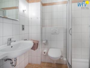 a white bathroom with a sink and a toilet at Haus Ebbe und Flut A - Ferienwohnung Deichläufer in Juist +15 photos