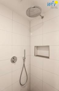 a white bathroom with a shower with a shower head at Haus Talita - Wohnung ECHO in Juist