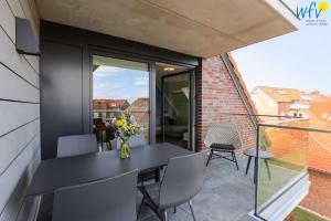 a balcony with a black table and chairs at Haus Talita - Wohnung PAPA in Juist
