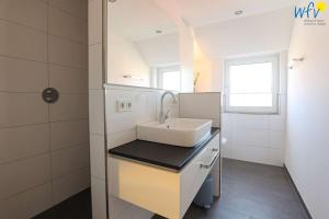 a bathroom with a white sink and a window at Haus Talita - Wohnung PAPA in Juist +8 photos