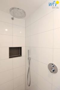 a white bathroom with a shower with a shower head at Haus Talita - Wohnung ROMEO in Juist