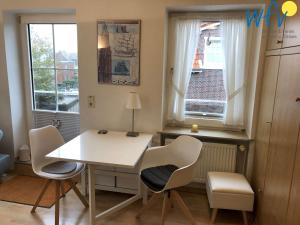 a white table and chairs in a room with windows at Haus Solaris - Ferienwohnung Lüttje Koje in Wangerooge +10 photos