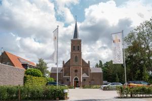 een kerk met twee vlaggen ervoor bij KerkHotel Biervliet in Biervliet